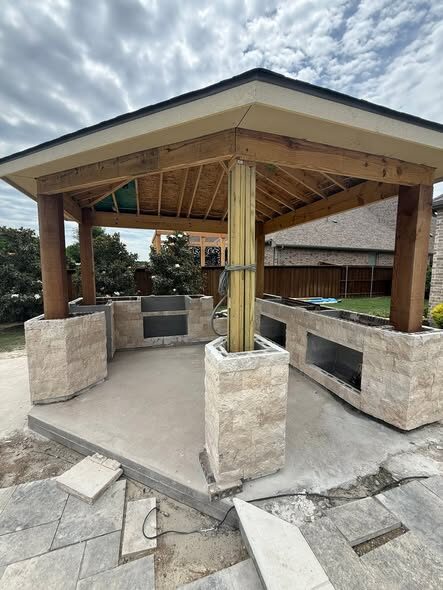 Custom stone outdoor fireplace built into a covered pavilion kitchen