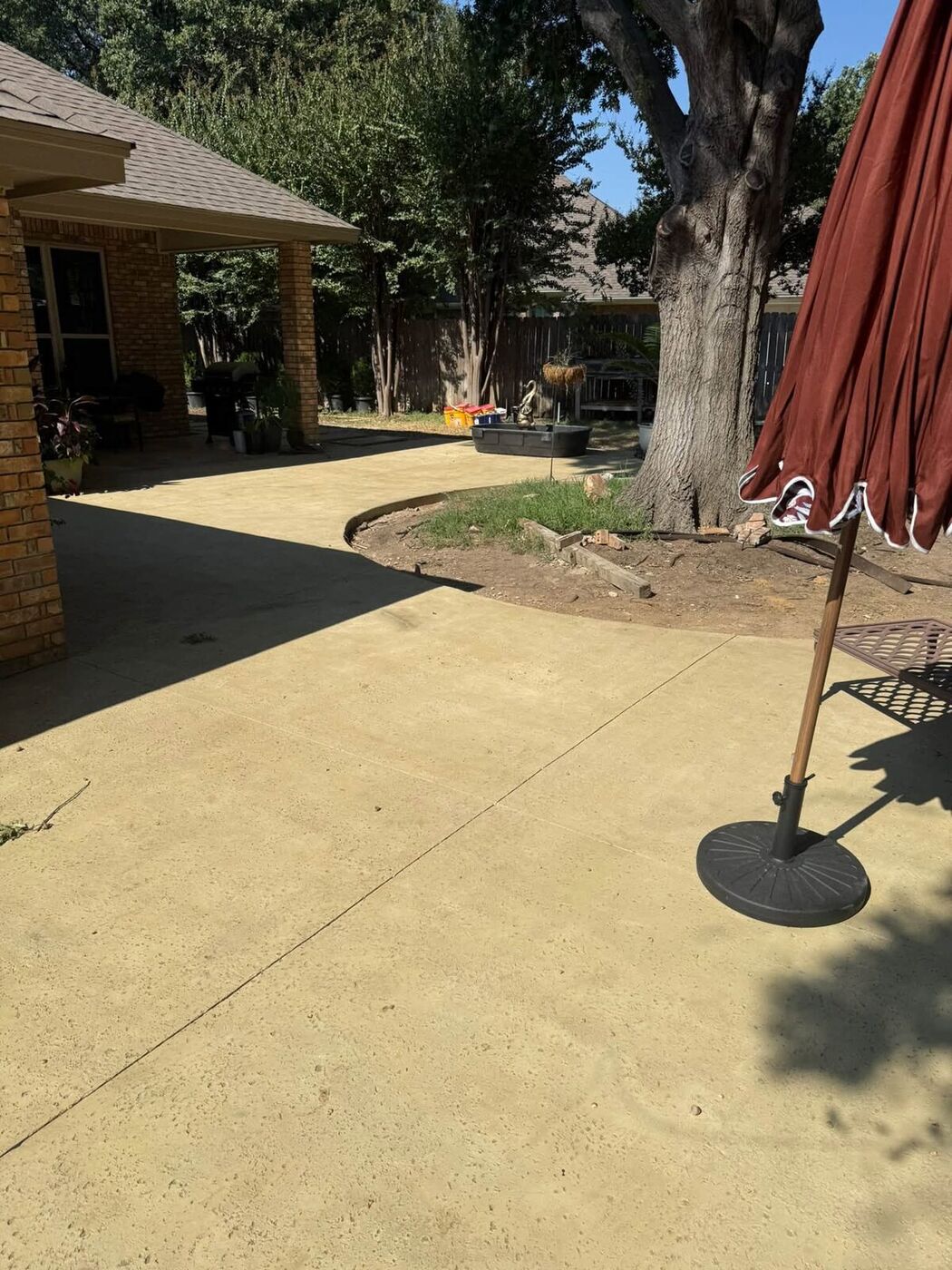 Stained concrete patio curving through a shaded backyard